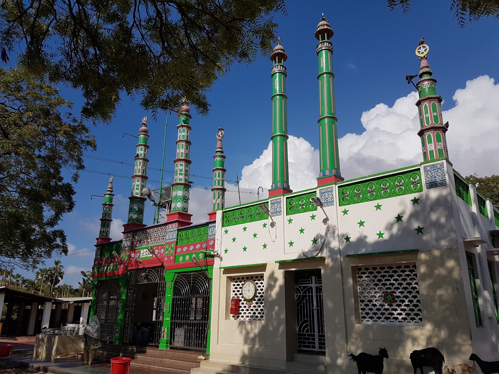 The mosque and shrine of Syed Ali Fathima, a small colorful white and green building with tall pillars coming out the roof.